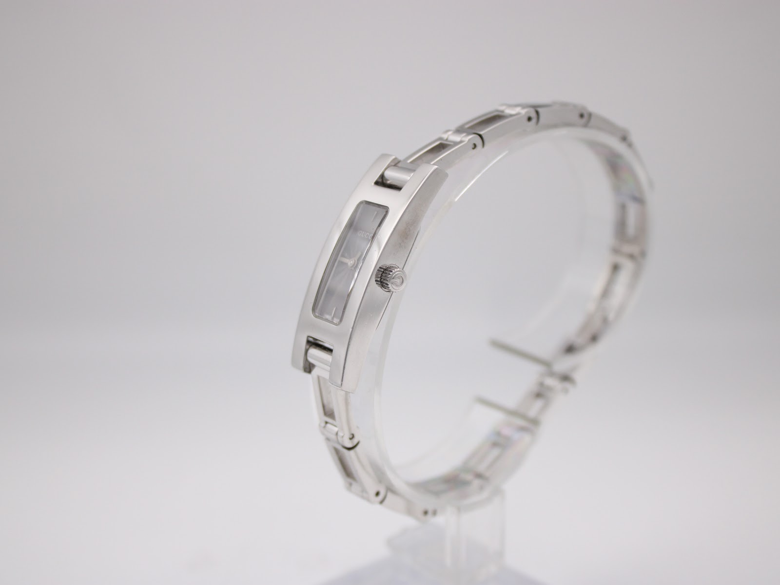 Side view of the Gucci 3900L watch on a clear stand, highlighting the slim profile and integrated bracelet design.