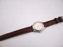 Overhead long shot of the Tissot PR 50 watch and its brown leather strap laid flat.