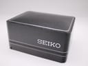 Original black textured Seiko watch box with white 'SEIKO' logo, closed.
