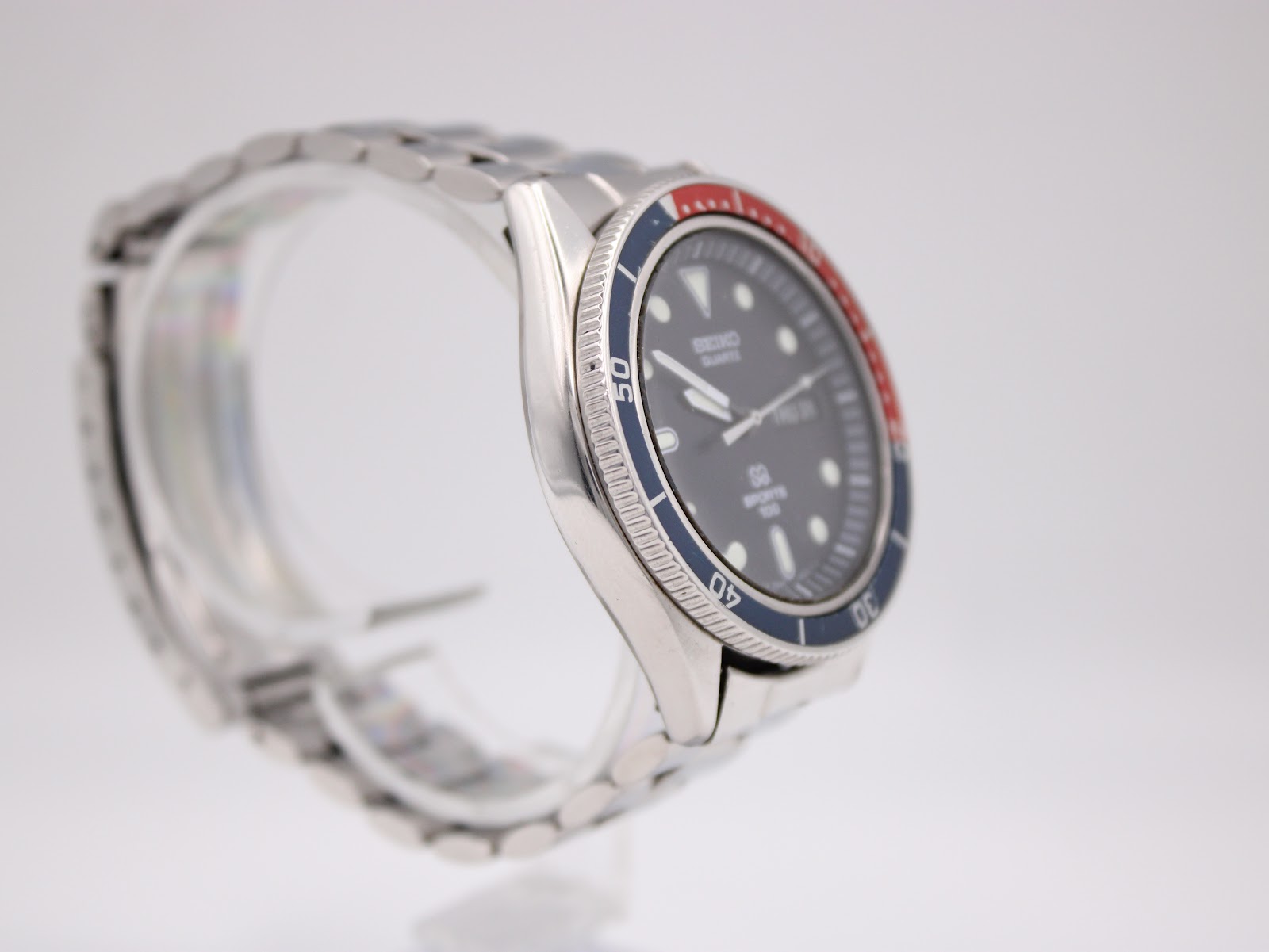 Left profile view of the Seiko diver watch on a clear display stand, showcasing the case shape and bracelet links.