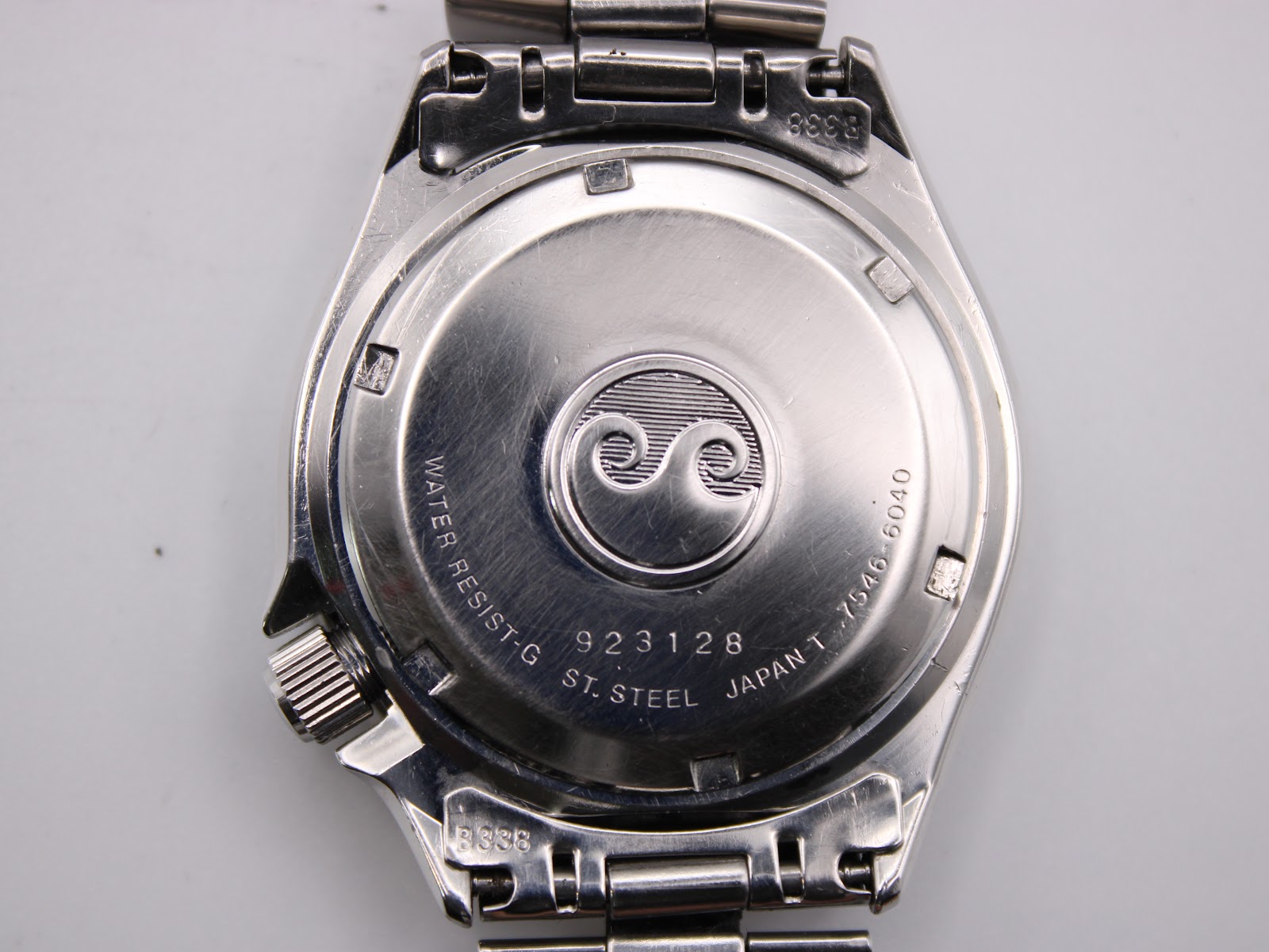 Close-up of the stainless steel case back, engraved with serial number 923128, model 7546-6040, and water resist marking.