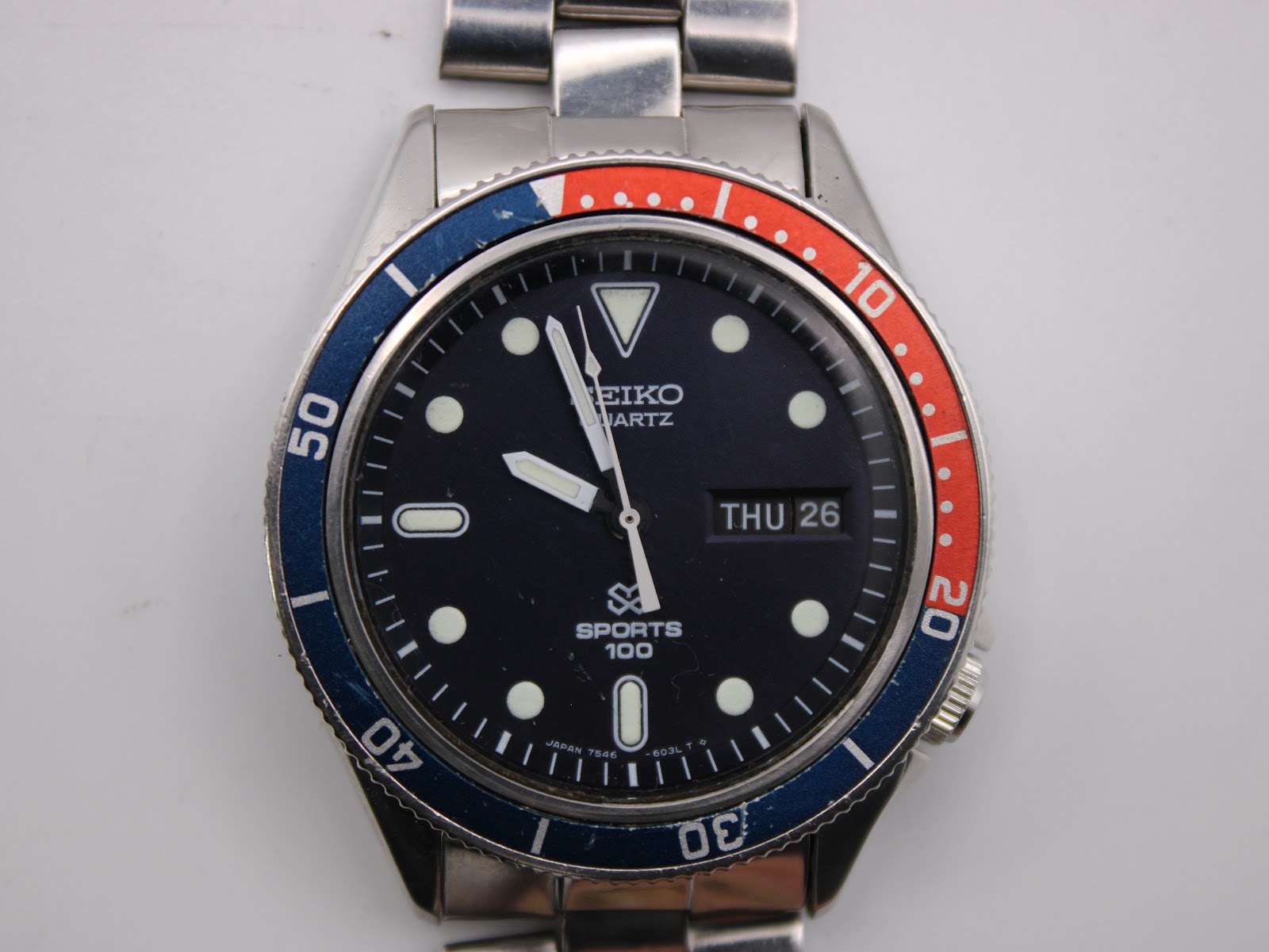 Overhead view of the Seiko 7546-6040 watch dial, highlighting the day-date complication and lumed indices.
