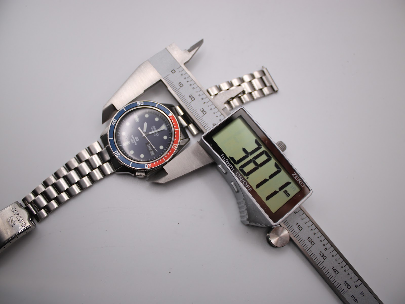 Top-down view of the watch being measured by a digital caliper, displaying a case diameter of 38.77 mm.