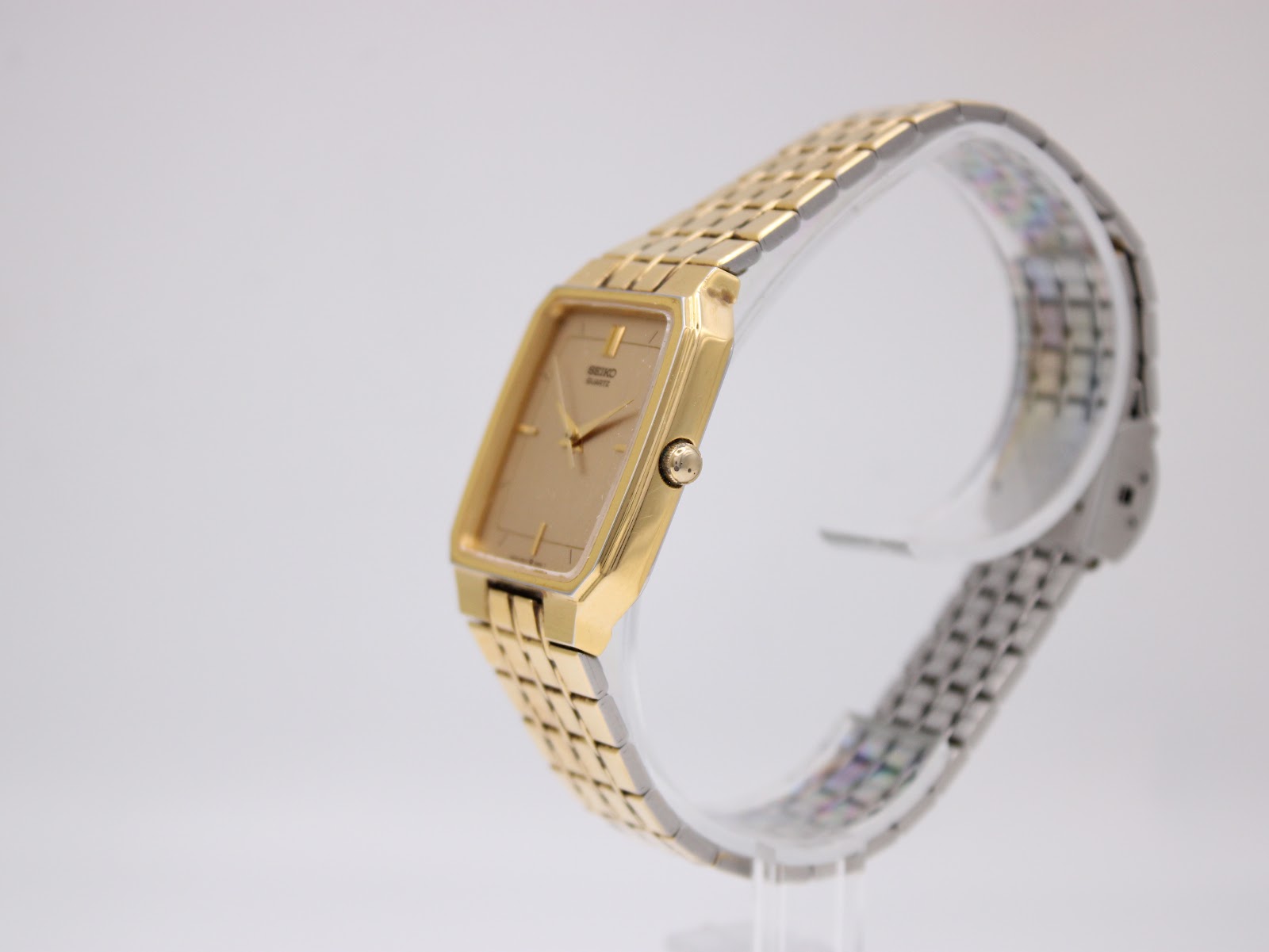 Side profile view of the gold tone Seiko 6531-5170 watch on a clear display stand, showing the crown.
