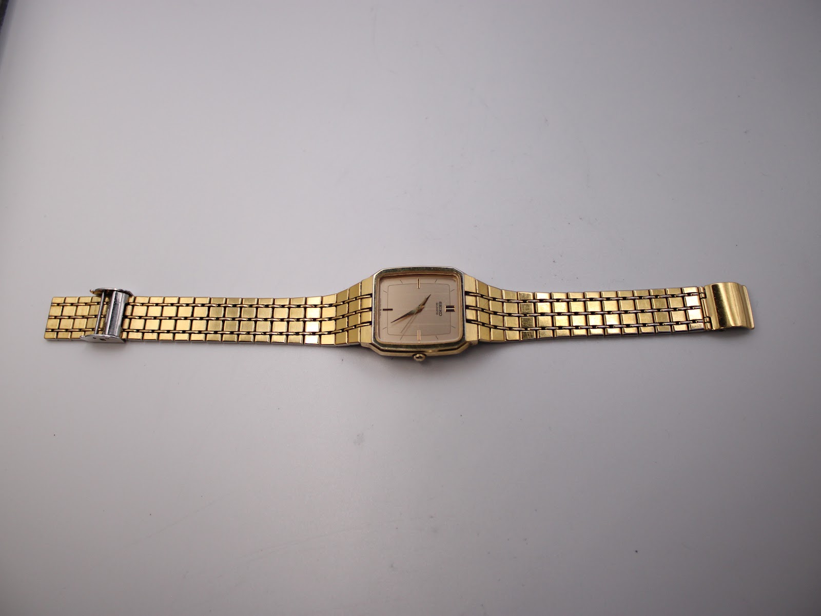 Full length top-down view of the gold tone Seiko 6531-5170 watch and integrated bracelet laid flat.