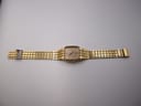Full length top-down view of the gold tone Seiko 6531-5170 watch and integrated bracelet laid flat.