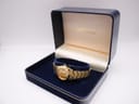 Gold tone Seiko watch resting in its original dark blue presentation box with gold lettering.