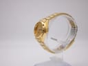 Side view of gold tone Seiko automatic watch on a clear stand, showing the crown.