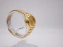 Other side view of gold tone Seiko automatic watch on a clear stand, showing bracelet links.