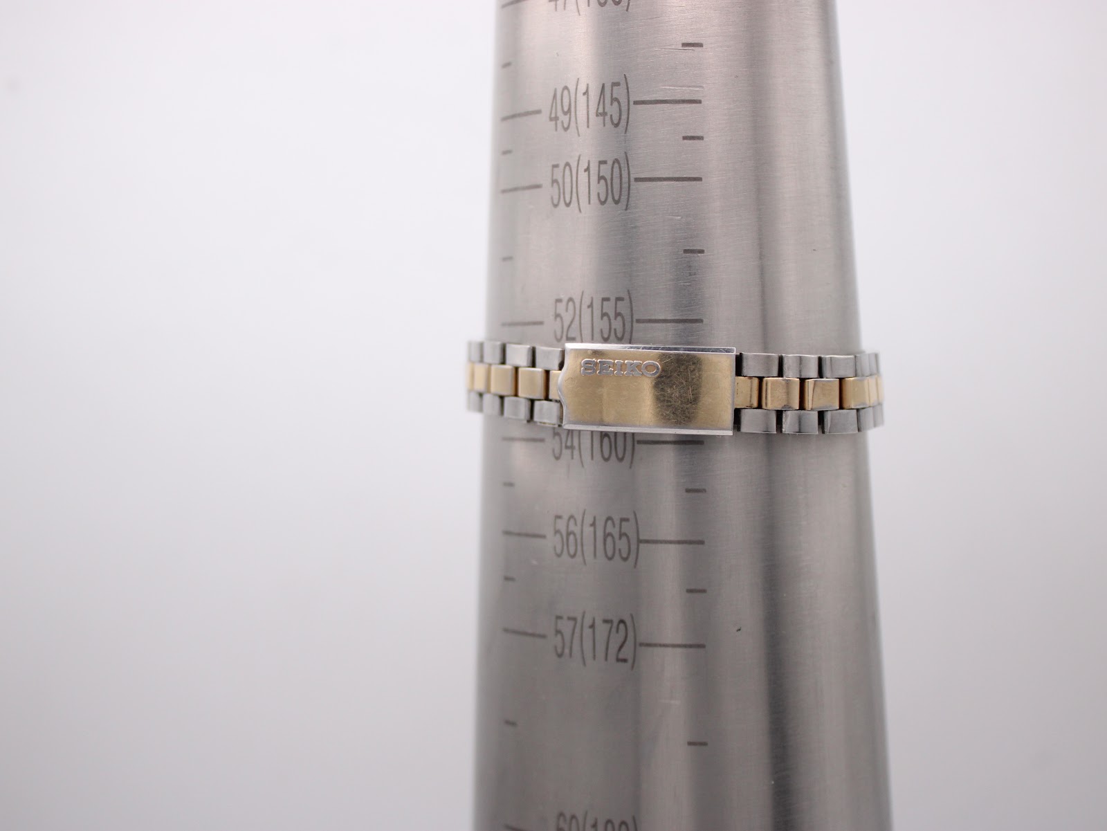 Seiko two-tone bracelet on a wrist sizing gauge, showing a measurement of approximately 155mm / 15.5cm.