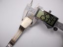 Overhead view of the Seiko 2A32-5060 watch being measured by a digital caliper, displaying an exact case width of 25.34mm.