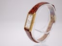 Angled view of the Seiko 2E20-6120, highlighting the slim gold-plated case and brown crocodile-embossed leather strap on a display stand.