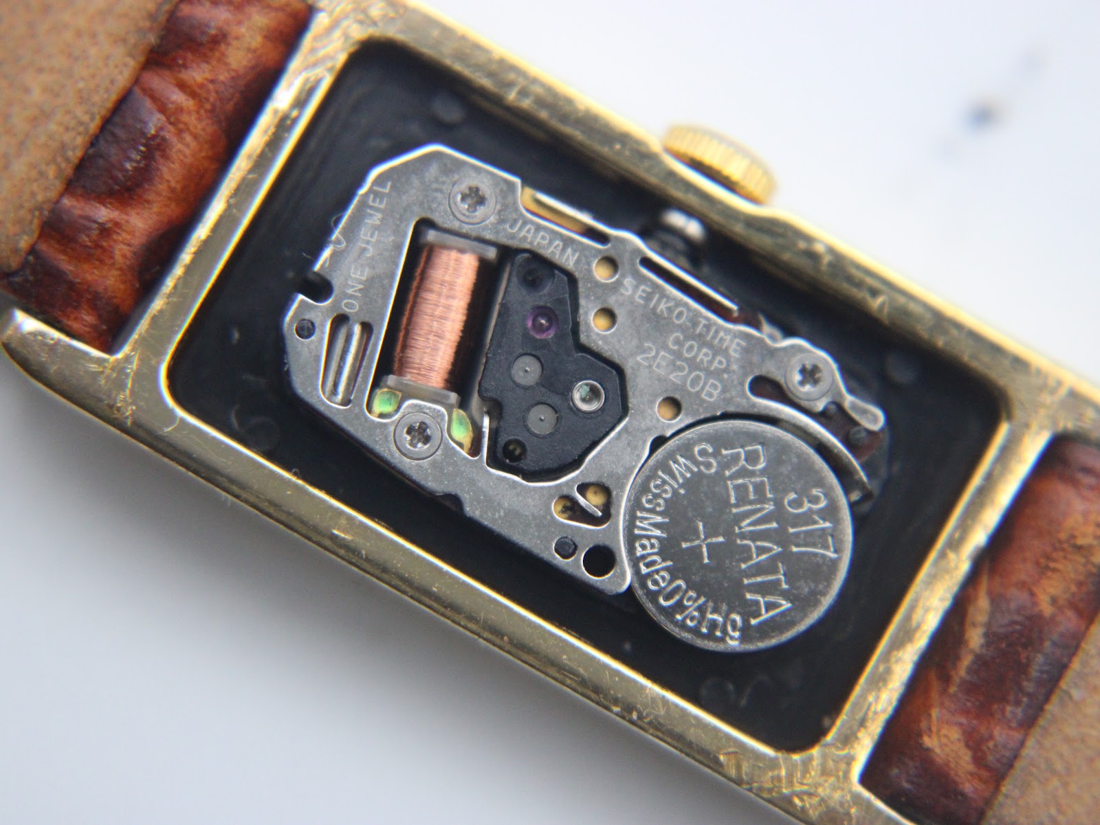 Macro shot of the Seiko 2E20B quartz movement inside the case, showing the fitted Renata 317 battery and 'ONE JEWEL' text.