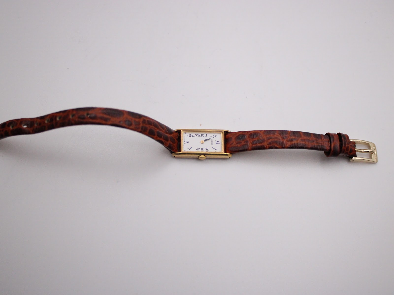 Overhead view of the Seiko 2E20-6120 watch laid flat, displaying the full length of the brown embossed leather strap and buckle.
