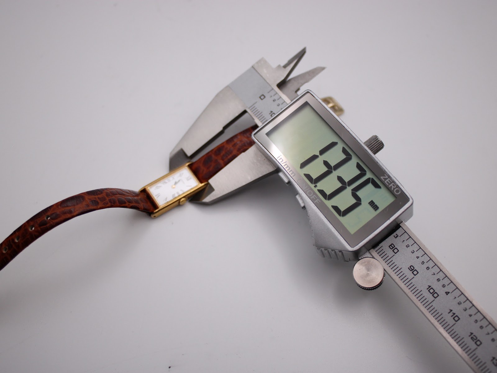 Digital caliper measuring the case width of the Seiko watch, showing a precise measurement of 13.35mm on the display.