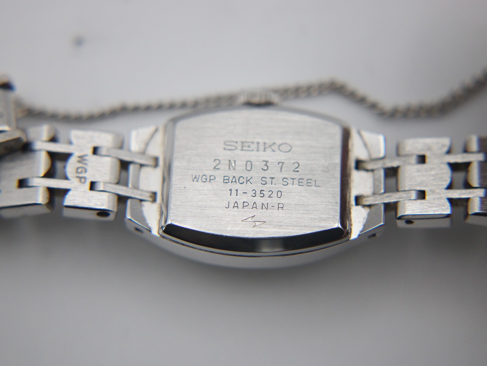 Close-up of the watch case back, engraved with "SEIKO 2N0372 WGP BACK ST. STEEL 11-3520 JAPAN-R".