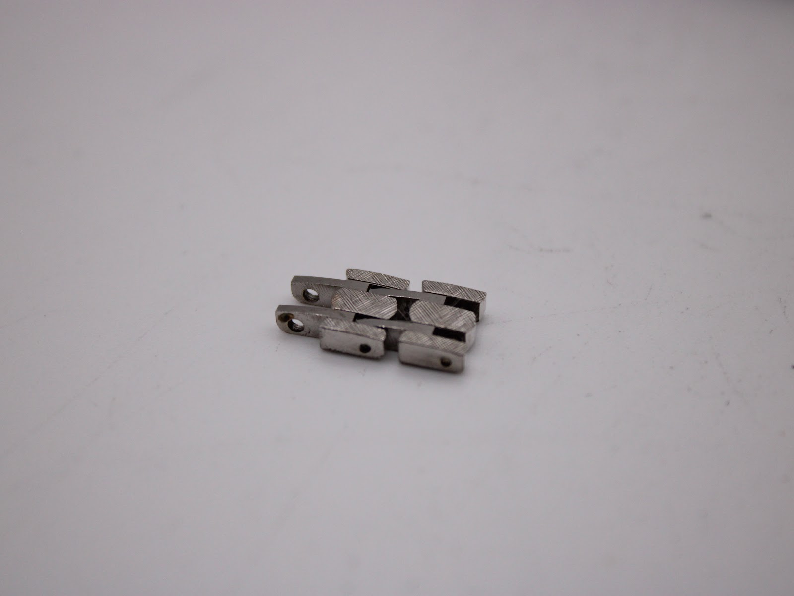 Two additional links for the integrated metal bracelet, showing the same textured finish as the main bracelet.