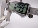 Digital caliper measuring the case width of the Seiko watch, displaying a precise measurement of 12.99mm.