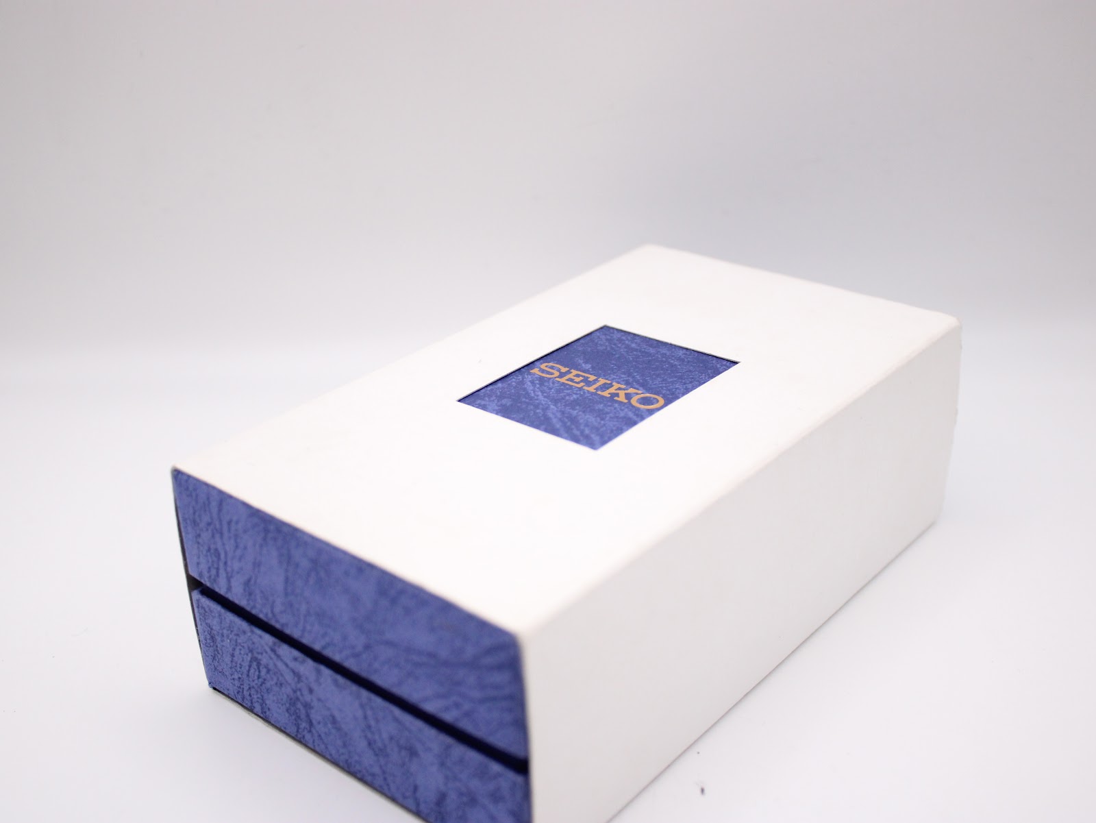 Outer white cardboard box for the Seiko watch, with a blue cutout revealing the "SEIKO" logo.