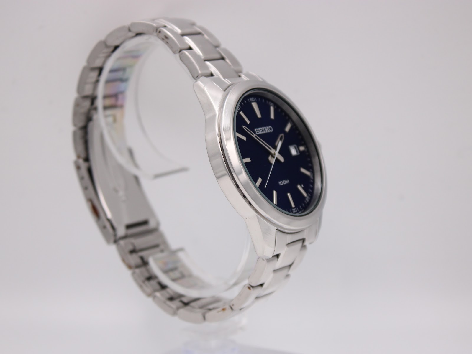 Close-up of Seiko 6N42-00E0 dial showing silver-toned dauphine hands with luminous inserts, double baton index at 12, and crisp date window at 3 o'clock