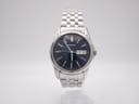 Front view of Seiko 7N43-0AM0 with navy blue sunburst dial, silver baton indices, and day-date window at 3 o'clock on stainless steel bracelet