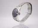 Side profile of Seiko 7N43-0AM0 showing round stainless steel case, polished bezel, and integrated five-link bracelet on a stand