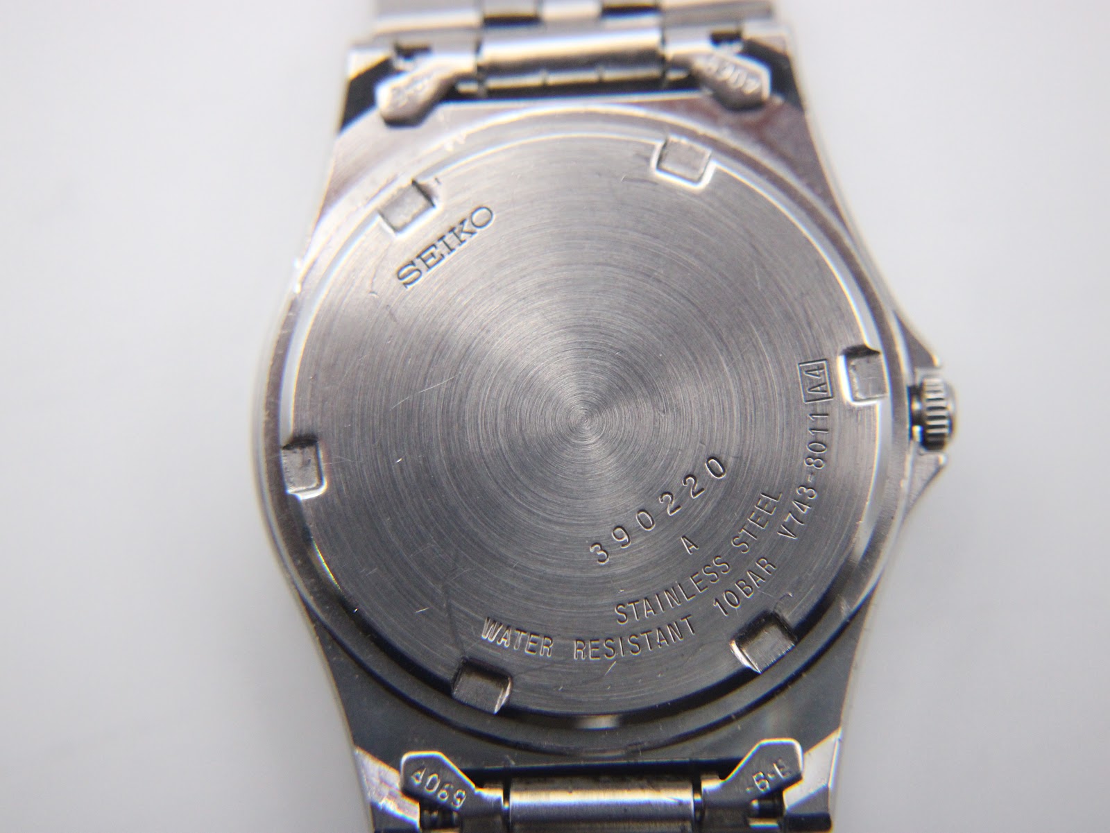 Close-up of the stainless steel case back showing model V743-8011 and serial 390220.