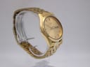 Opposite angled side view of the gold-tone Seiko 7N43-9011 watch on a stand, highlighting the case and bracelet.