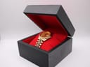 Side view of the gold-tone Seiko watch resting inside a black presentation box with a red velvet interior.