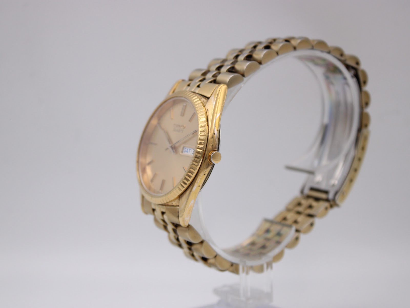 Angled side view of the Seiko watch on a clear display stand, showing the fluted bezel and bracelet.