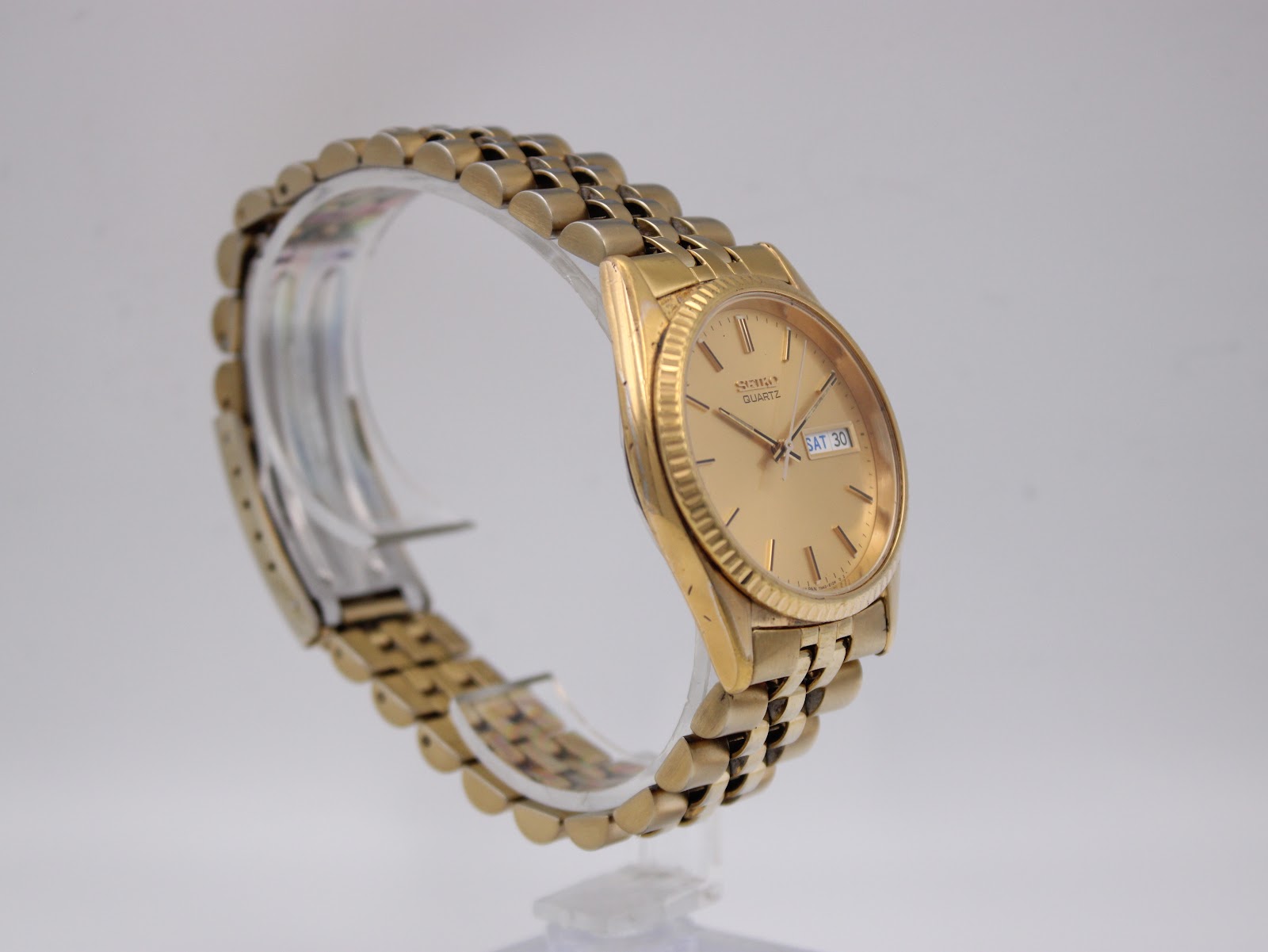 Another angled side view of the Seiko watch on a clear display stand, highlighting the dial and bracelet.