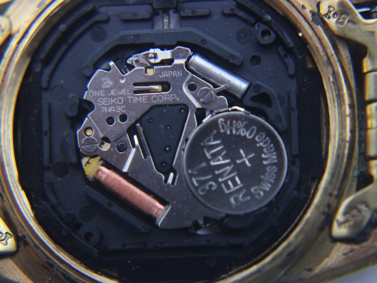 Extreme close-up of the Seiko 7N43C quartz movement with a Renata 371 battery installed, showing internal components.