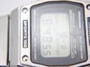 Extreme close-up of the digital LCD display and acrylic crystal, showing visible surface scratches on the crystal.