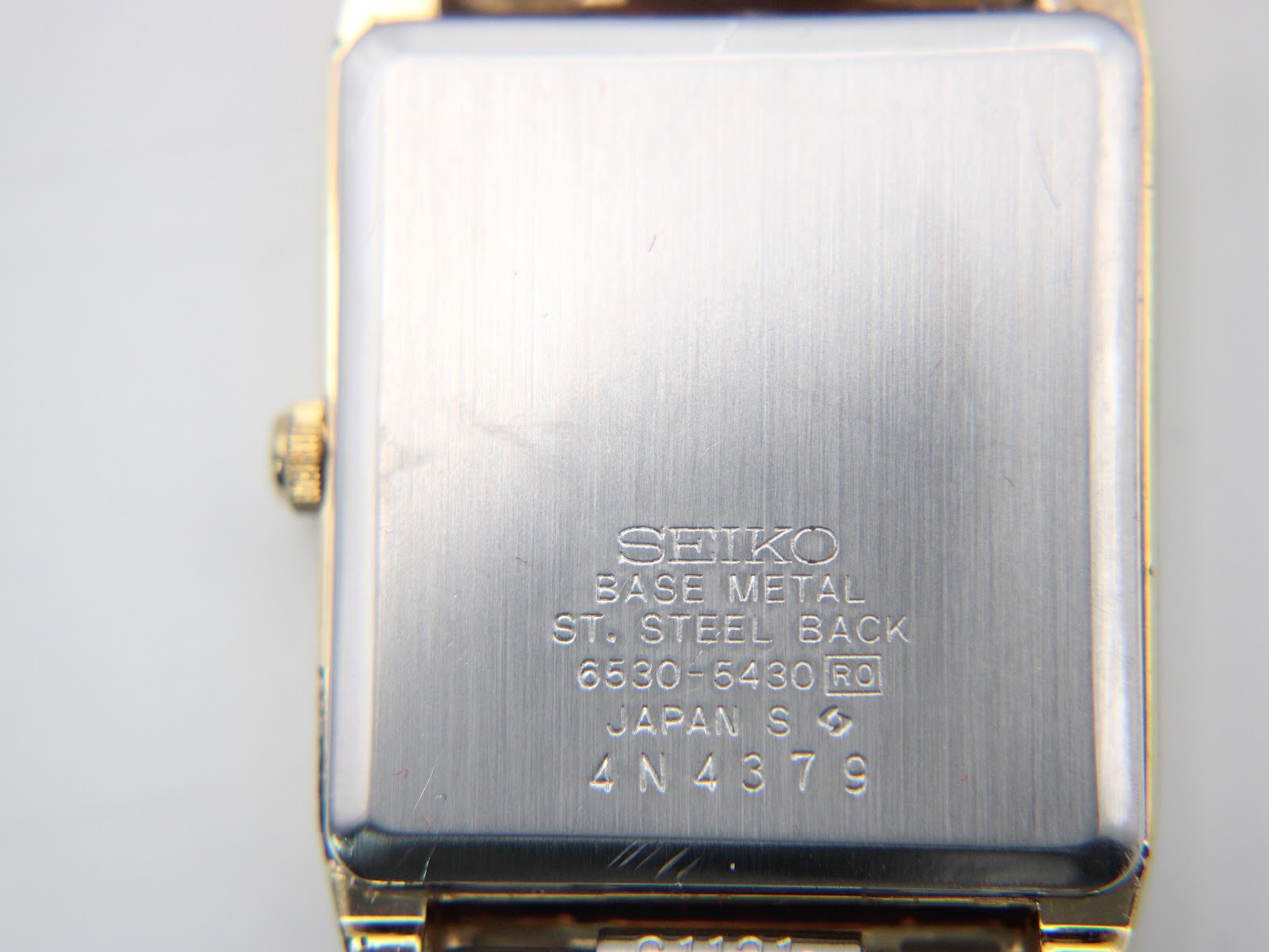 Close-up of the brushed stainless steel case back of the Seiko watch, showing model 6530-5430 and serial number 4N4379 engravings.