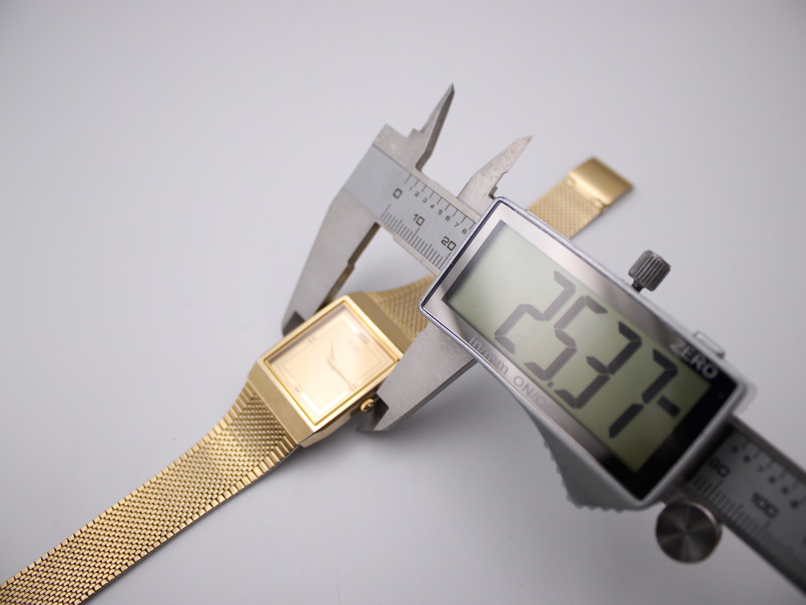 Digital caliper measuring the case width of the gold tone Seiko watch, displaying a precise measurement of 25.37mm.