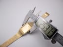Digital caliper measuring the case width of the gold tone Seiko watch, displaying a precise measurement of 25.37mm.