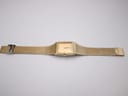 Top-down view of the entire gold tone Seiko watch with its integrated mesh bracelet laid flat.
