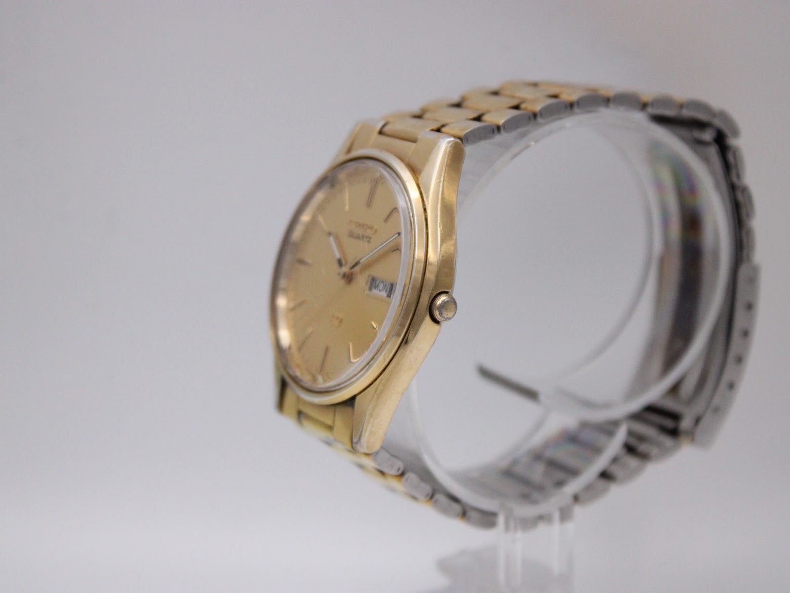 Side view of the Seiko gold-tone watch on a display stand, showing the case profile and bracelet.