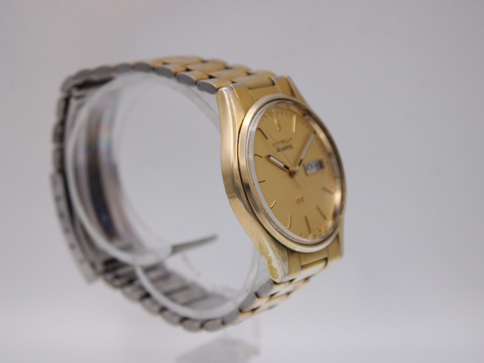 Opposite side view of the Seiko watch on a display stand, highlighting the integrated gold-tone bracelet.