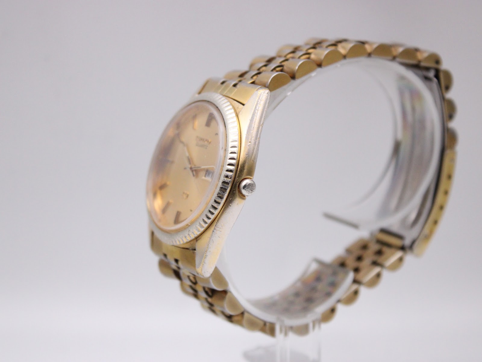 Side view of the Seiko watch, showing the fluted bezel and gold-tone case, with some wear visible.