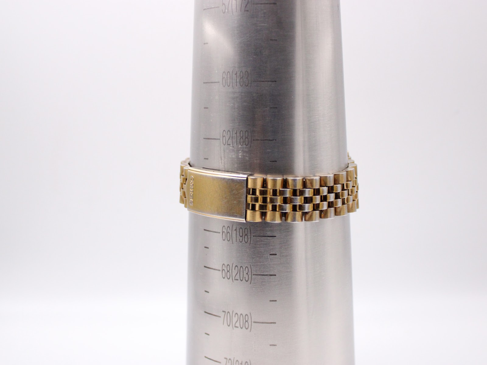 The gold-tone jubilee bracelet on a wrist sizing gauge, indicating a maximum wrist circumference of approximately 19.3 cm.