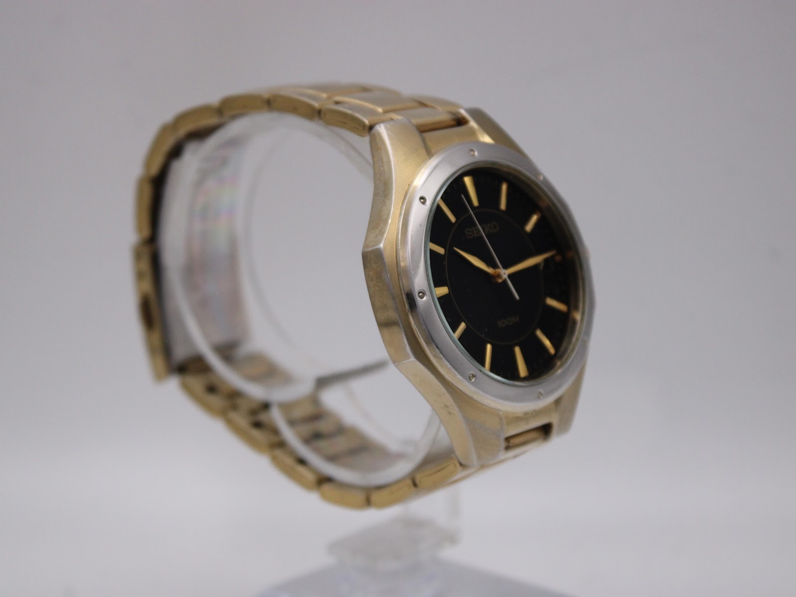 Another angled view of the Seiko watch on a clear stand, highlighting the dial and bracelet flow.
