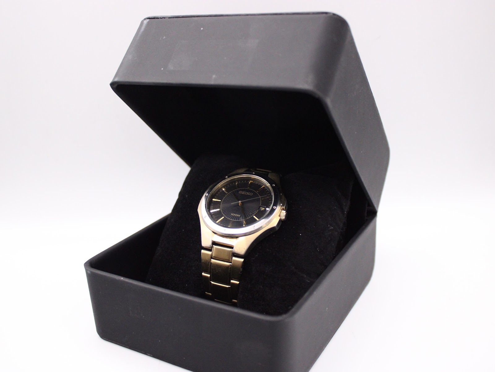 The gold tone Seiko watch presented inside a generic open black display box.