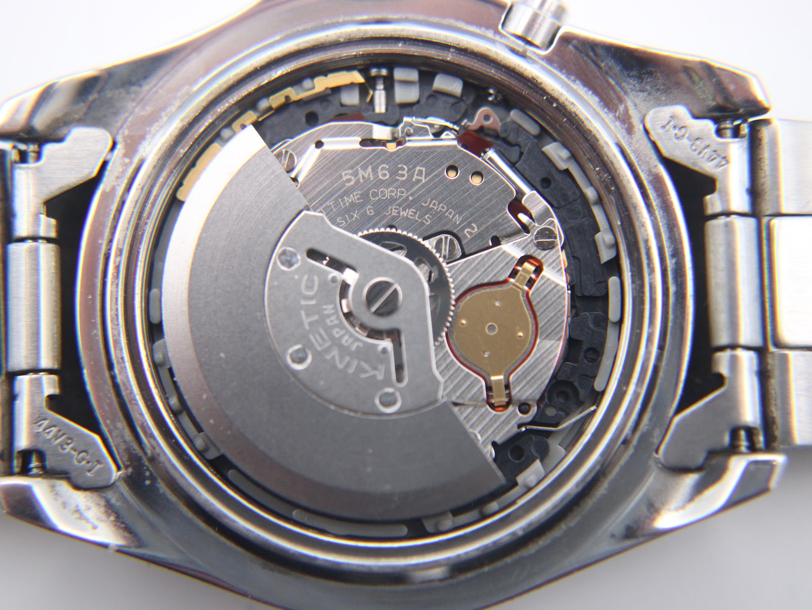 Close-up view of the Seiko Kinetic 5M63A movement inside the open case, showing "KINETIC", "JAPAN", and "SIX 6 JEWELS" engravings.