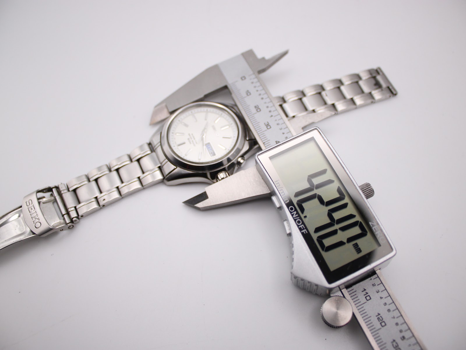 Overhead view of the Seiko Kinetic watch being measured by a digital caliper, displaying a case diameter of 42.40 mm.
