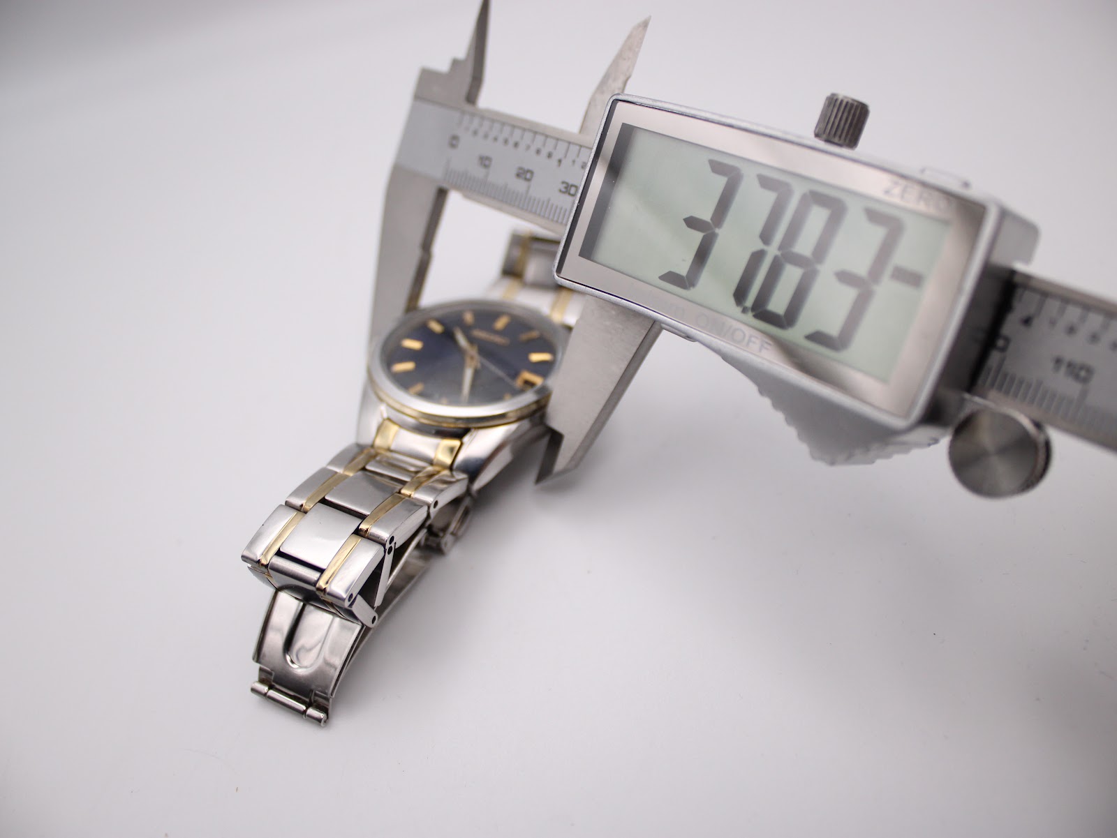 Digital caliper measuring the case diameter of the watch, displaying a measurement of 37.83mm.