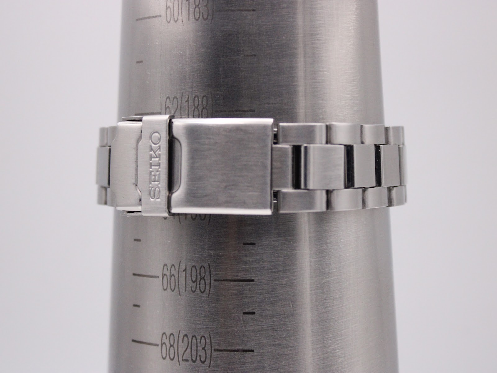 Wrist sizing gauge showing the stainless steel bracelet and signed Seiko deployant clasp, measuring approx 19.3cm.