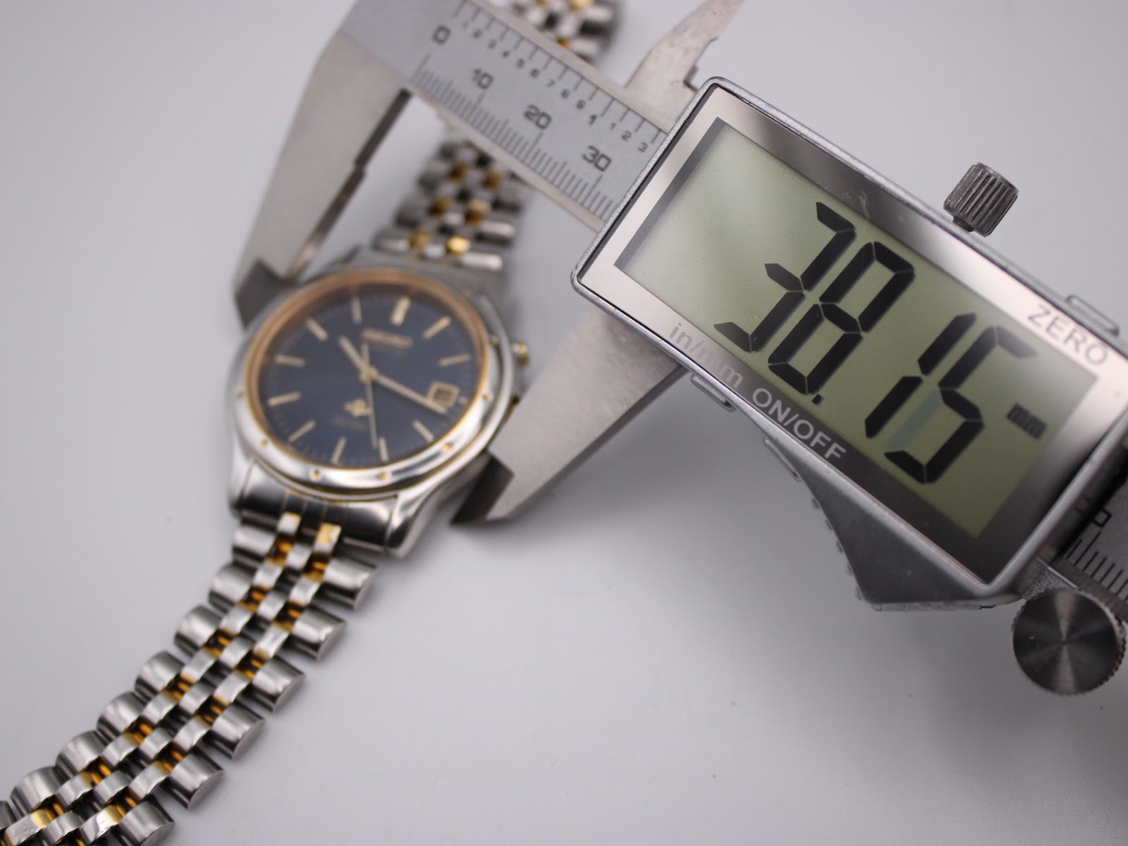 Digital caliper measuring the case diameter of the Seiko watch, displaying 38.15 mm.