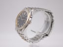 Angled side view of the Seiko watch, showing the silver case, gold-tone bezel, crown, and power reserve pusher.