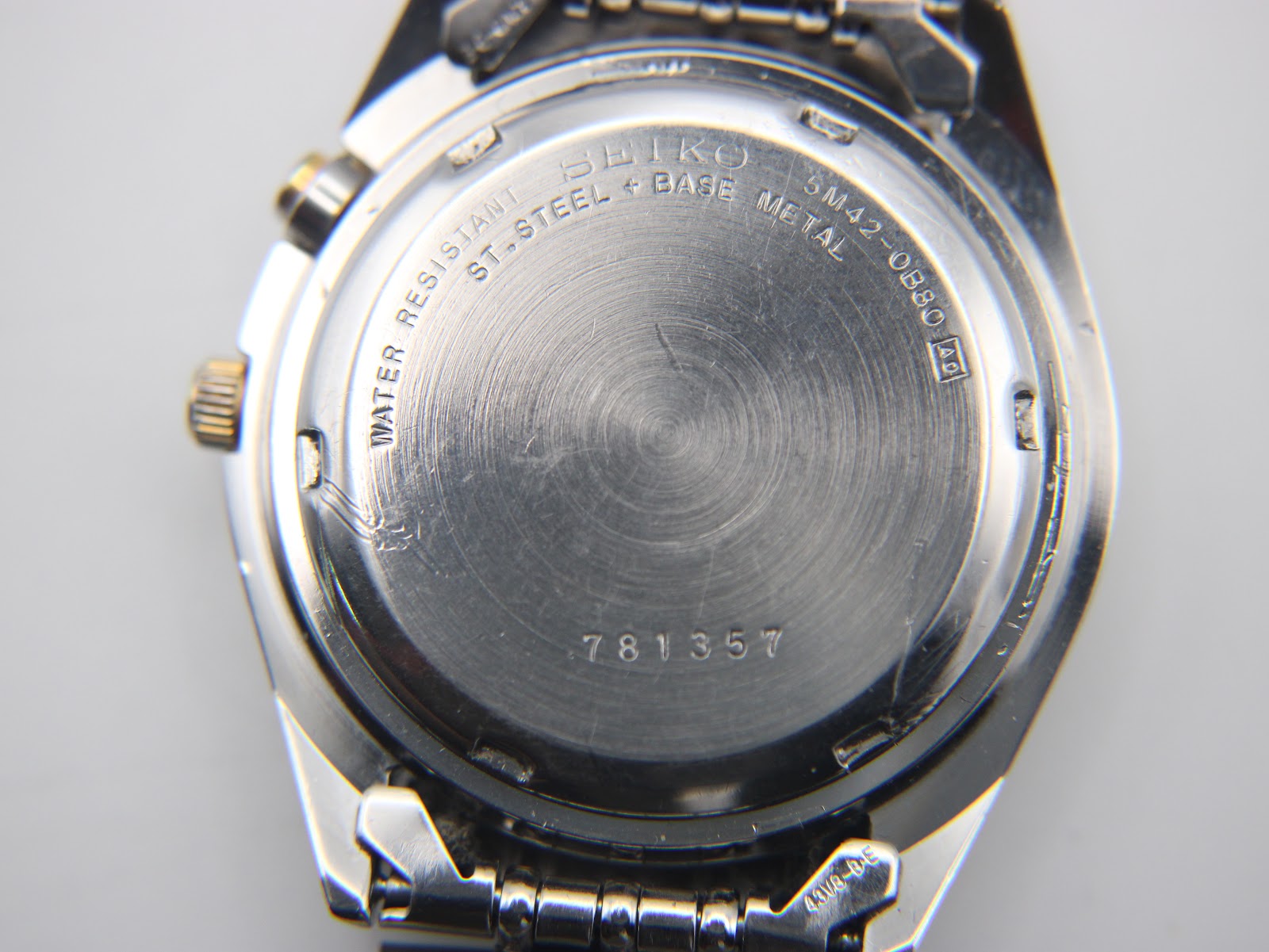 Close-up view of the stainless steel case back, engraved with 'SEIKO WATER RESISTANT ST.STEEL + BASE METAL 5M42-0B80 A4' and serial '781357'.